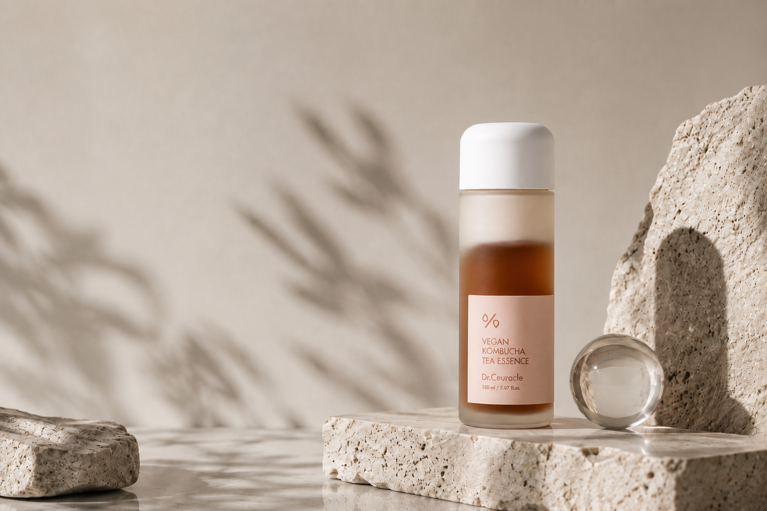 Dr.Ceuracle Vegan Kombucha Tea Essence on warm travertine in sunlit studio